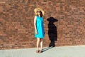 Slender Caucasian woman in blue dress and straw hat with fatty shadow on the wall. The concept of inadequate perception of one`s