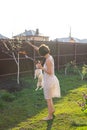 Slender cute young woman plays with her beloved funny dog in the yard on a sunny summer day. Lovely pet concept. Royalty Free Stock Photo