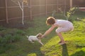 Slender cute young woman plays with her beloved funny dog in the yard on a sunny summer day. Lovely pet concept. Royalty Free Stock Photo