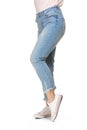 Slender female legs in blue jeans and sport shoes isolated on white background Royalty Free Stock Photo