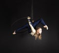 Slender girl-aerial acrobat in a blue and white suit with long hair, performs exercises in the air ring