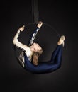 Slender girl-aerial acrobat in a blue and white suit with long hair, performs exercises in the air ring