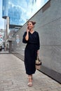 Tall slim girl walking down the street and talking on a smartphone Royalty Free Stock Photo