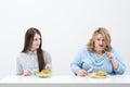 Slender girl eats healthy food, Fat woman eats harmful fast food. On a white background, the theme of diet and proper Royalty Free Stock Photo