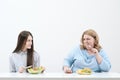 Slender girl eats healthy food, Fat woman eats harmful fast food. On a white background, the theme of diet and proper Royalty Free Stock Photo