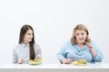 Slender girl eats healthy food, Fat woman eats harmful fast food. On a white background, the theme of diet and proper Royalty Free Stock Photo