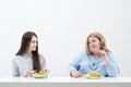 Slender girl eats healthy food, Fat woman eats harmful fast food. On a white background, the theme of diet and proper Royalty Free Stock Photo