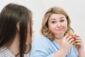 Slender girl eats healthy food, Fat woman eats harmful fast food. On a white background, the theme of diet and proper Royalty Free Stock Photo