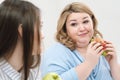 Slender girl eats healthy food, Fat woman eats harmful fast food. On a white background, the theme of diet and proper Royalty Free Stock Photo