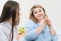 Slender girl eats healthy food, Fat woman eats harmful fast food. On a white background, the theme of diet and proper Royalty Free Stock Photo