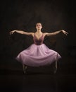 A slender girl in a pink skirt and beige top dancing ballet