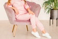 a slender girl in a pink suit sits in a chair Royalty Free Stock Photo