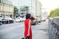 A slender girl in a red dress is walking along the sidewalk. Royalty Free Stock Photo