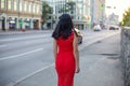 A slender girl in a red dress is walking along the sidewalk. Royalty Free Stock Photo
