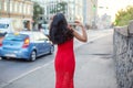 A slender girl in a red dress is walking along the sidewalk. Royalty Free Stock Photo