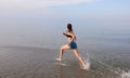 slender girl running with very wide strides on the sea shore