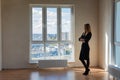 Slender girl stands at a large stained glass window in an empty room