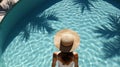 A slender girl in a swimsuit and beach hat walks into the pool. Royalty Free Stock Photo