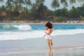 A slender girl in white clothes runs along the beach against the background of the sea. Royalty Free Stock Photo