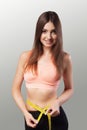 Slender girl. A young woman measuring her thin waist with a ribbon. Diet and Sports. The concept of beauty and health. On a gray Royalty Free Stock Photo