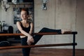 Slender smiling red haired woman stretching leg on ballet barre in classroom Royalty Free Stock Photo