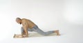 A slender muscular man with a bare torso practices yoga on a white background. Sport, meditation and the