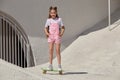 A slender tall girl smiles and rides a skateboard. Summer holidays.