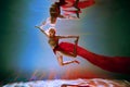 girl with an athletic figure and blond hair, with red material, in a ballet pose underwater Royalty Free Stock Photo