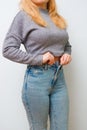 A slender woman fastens a button of her blue jeans. Weight ungain woman getting dressed wearing jeans. Close up of girl buttoning Royalty Free Stock Photo