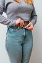 A slender woman fastens a button of her blue jeans. Weight ungain woman getting dressed wearing jeans. Close up of girl buttoning Royalty Free Stock Photo