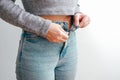 A slender woman fastens a button of her blue jeans. Weight ungain woman getting dressed wearing jeans. Close up of girl buttoning Royalty Free Stock Photo