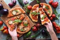 Slender woman hands reaching for healthy vegetarian pizza. Homemade rustic pizzas with aubergines, bell peppers, basil and tomato Royalty Free Stock Photo