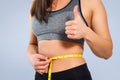 A slender woman measures her waist with a measuring tape. On a blue background Royalty Free Stock Photo