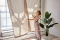 Window shading by slim woman in room. Royalty Free Stock Photo