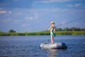 Young blonde girl fishing on boat in lake