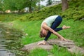 Slender young brunette yogi performs challenging yoga exercises on the green grass in the summer against the backdrop of nature Royalty Free Stock Photo