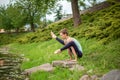 Slender young brunette yogi performs challenging yoga exercises on the green grass in the summer against the backdrop of nature Royalty Free Stock Photo