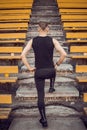 A slender young man in black sportswear stands in front of the stairs stadium stands. ready for action, step to victory, challenge