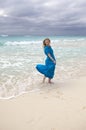 Slender young woman with long hair fluttering in the wind in a blue dress on the shore of a stormy sea on a sandy beach Cuba, Var Royalty Free Stock Photo