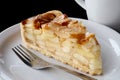 A slice of apple pie on white ceramic plate with fork. Black background. Royalty Free Stock Photo