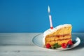 Slice of birthday cake with candle and berries Royalty Free Stock Photo