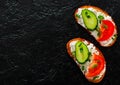 Slice of bread with cream cheese, cucumber, tomato on a black stone board. with copy space. top view Royalty Free Stock Photo