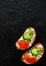 Slice of bread with cream cheese, cucumber, tomato on a black stone board. with copy space. top view Royalty Free Stock Photo