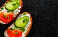 Slice of bread with cream cheese, cucumber, tomato on a black stone board. with copy space. top view Royalty Free Stock Photo