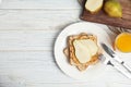 Slice of bread with peanut butter and pear on white wooden table. Space for text Royalty Free Stock Photo