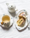 Slice of cake with cranberries, white chocolate and cup of green tea on a light background, top view