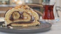 A slice of cake on serveware next to a glass of tea drinkware