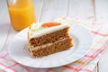 Slice of carrot cake Pastel de zanahoria with icing and marzipan carrot on white background with carrot juice