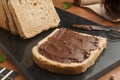 Slice of cereal bread with chocolate hazelnut cream spread on a black granite cutting board Royalty Free Stock Photo