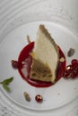 Slice cheesecake with forest fruits Ã¢â¬â red currants, mint and gold leaf on white plate, brown background